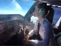 a female pilot sitting in the cockpit of an airplane with headphones on her ears