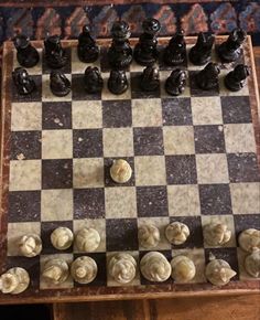 the chess board is made out of marble and has black pieces on it, including one pawn