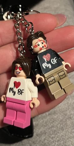 two legos are holding on to the same keychain as they stand next to each other