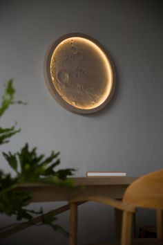 a circular light fixture mounted on the wall above a table with a plant in front of it