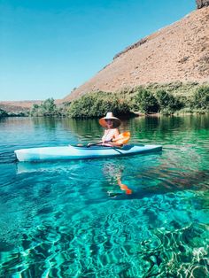 a man is paddling his kayak in clear blue water