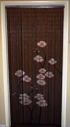 a bamboo screen with flowers on it in front of a door that has the blinds closed