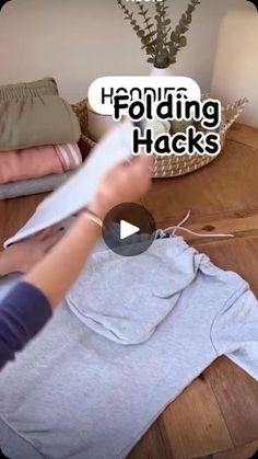 a person cutting fabric with scissors on top of a wooden table in front of pillows