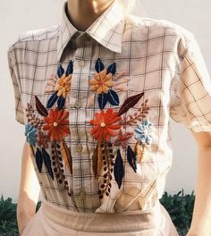 a woman wearing a shirt with flowers and feathers on it