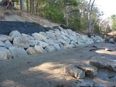 a pile of rocks sitting on the side of a dirt road next to a forest