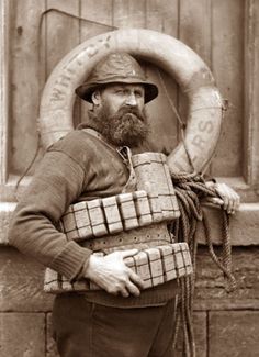 an old photo of a man with a beard wearing a helmet and holding a large object