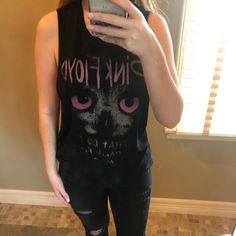 a woman taking a selfie in front of a mirror wearing black ripped jeans and a pink floyd tank top