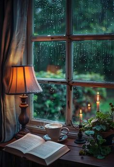 an open book sitting on top of a table next to a window filled with raindrops