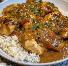 a white plate topped with rice and meat covered in gravy on top of a table