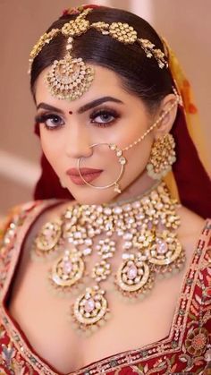 a woman in a red and gold outfit with jewelry on her neck, wearing a nose ring