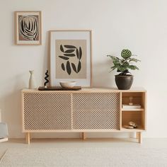 a living room with a plant and pictures on the wall above it's entertainment center