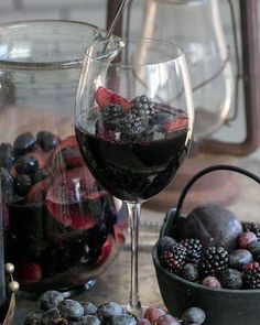 a glass of red wine next to a bowl of berries