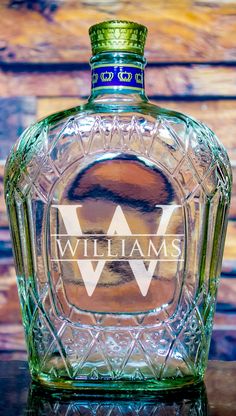 a glass bottle sitting on top of a table next to a wooden wall with the word williams