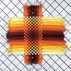 an orange and yellow piece of art made out of strips of paper with pins sticking out of it