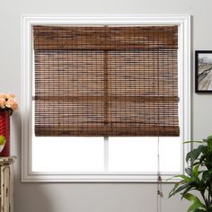 an image of a bamboo blinds in the living room with flowers on the window sill