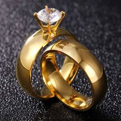 two gold wedding rings with a diamond in the middle