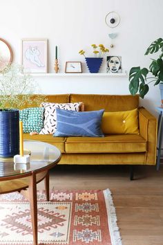 a living room with yellow couches and blue vases on the coffee table in front of it