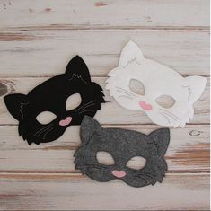 three cat masks are sitting on a wooden surface