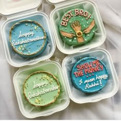 four decorated cookies in plastic containers on a bed