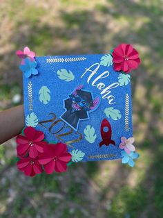 a hand holding up a blue card with flowers on it and the words aloha