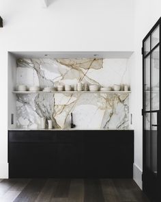 a kitchen with marble counter tops and black cabinets in the center, along with wooden flooring