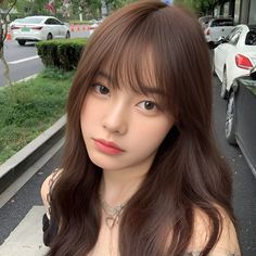 a woman with long brown hair standing on the sidewalk