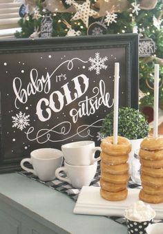 a table topped with donuts covered in frosting next to a sign that says baby it's cold outside