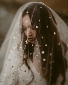 a woman wearing a wedding veil with stars on her head and hair in the wind