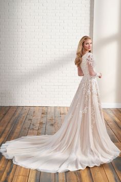 a woman in a wedding dress stands on a wooden floor and looks off to the side