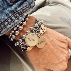 a close up of a person's arm wearing two bracelets with charms on them