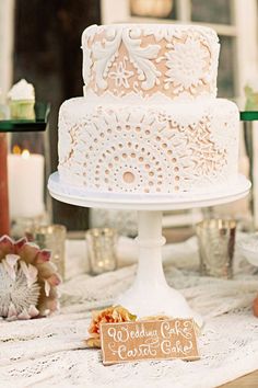 a white wedding cake sitting on top of a table next to other desserts and candles