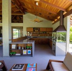 a large open kitchen and living room area with wood ceiling beams, wooden furniture, and an island in the middle