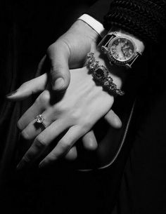 black and white photograph of two people holding each other's hands with rings on their fingers