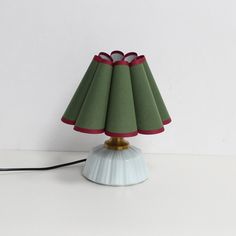 a lamp that is on top of a white table with a red and green shade