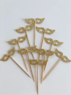 gold masquerade masks on top of toothpicks with glittery eyes and tails