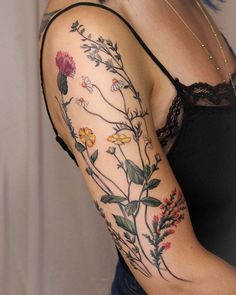 a woman's arm with flowers and leaves on it