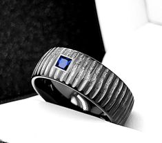 Hammered Black Tungsten Ring with Blue Sapphire Stone Setting, Men's Wedding Band, Men's Ring, His Promise Ring, Anniversary Gift- 7 mm, 8 mm, 9 mm. We accept custom orders Specification Carbide Wedding Bands *STONE - Blue Sapphire 2,5 mm in diameter *FINISH BRUSHED *THICKNESS 1.8 MM - 2.2 MM *WEIGHT 4 - 16 GRAMS * COMFORT FIT AND SIZING *SIZES AVAILABLE 4-16 US INCLUDING 1/2 SIZES *DURABLE *HYPOALLERGENIC Discover for yourself unique and masculine qualities of Tungsten Carbide Wedding Bands and Masculine Qualities, Mens Wedding Bands Blue, Male Engagement Ring, Gift For Husband Anniversary, Tungsten Engagement Rings, Mens Wedding Bands Black, Tungsten Jewelry, Black Tungsten Rings, Tungsten Carbide Wedding Bands