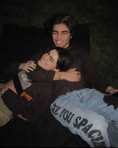 two people laying on the ground hugging each other