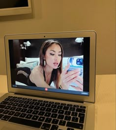 an open laptop computer sitting on top of a white table next to a cell phone