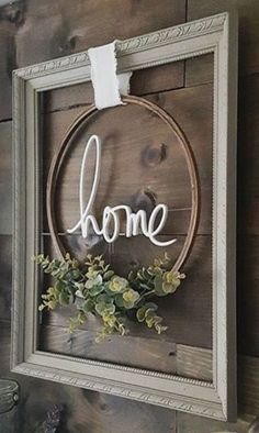 a sign that says home hanging on a wall next to a vase with flowers in it