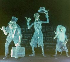 three people dressed in costumes and hats are standing on stage with their hands out to the side