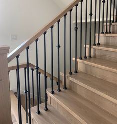 a wooden staircase with black railing and handrails