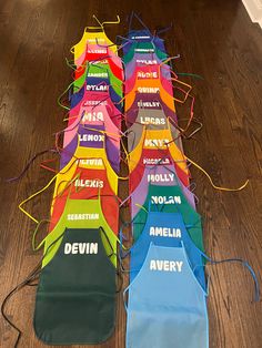 a long row of aprons with name tags on them sitting on top of a wooden floor