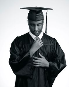 a black and white photo of a man wearing a graduation cap, gown and tie