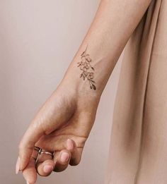 a woman's hand with a small tattoo on it, holding the arm of another person