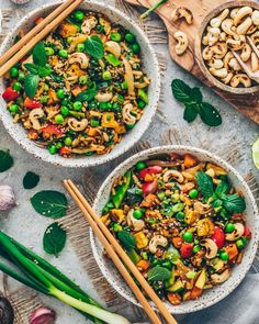 two bowls filled with vegetable stir fry next to chopsticks and vegetables on a table