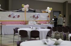 a banquet hall with tables and chairs set up for a formal function, decorated with balloons and streamers