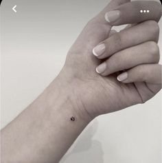 a woman's hand with a tiny black dot tattoo on the middle of her left wrist