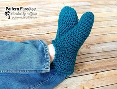 a pair of blue crocheted mittens sitting on top of a wooden floor