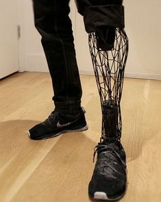 a person standing on top of a hard wood floor next to a white wall and black shoes